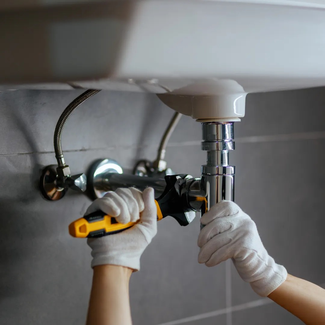 Technician repairing sink plumbing and adjusting fittings